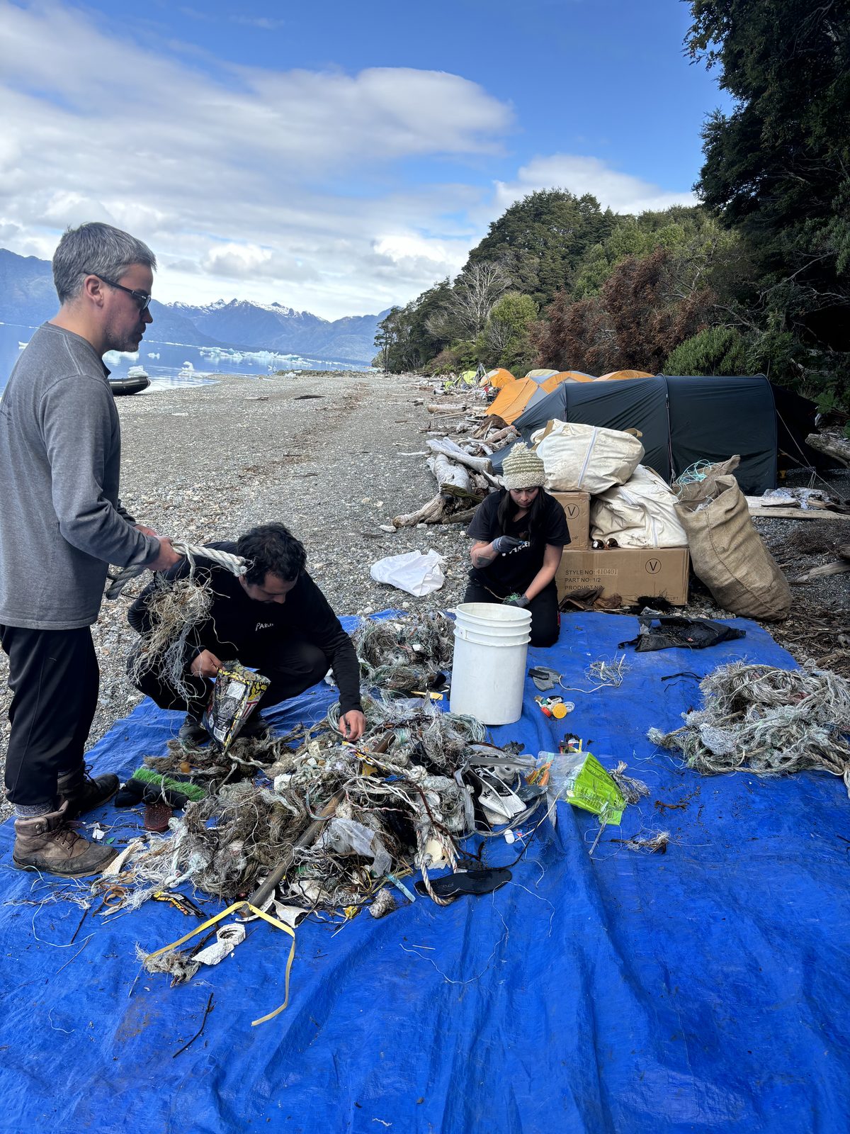 Clasificación de redes y cuerdas recogidas en la playa, sobre una lona azul